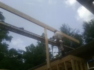 Carpenter setting a ridge beam over a new addition frame — Ice Dam Removal by Roofing Brothers in Sykesville