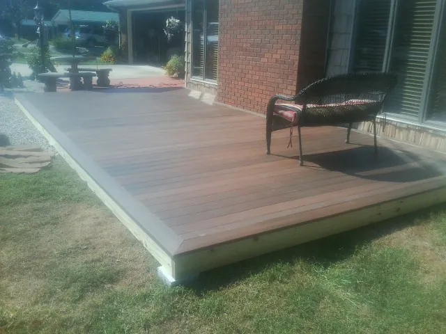 New wood deck and wicker chair beside a brick house in Sykesville