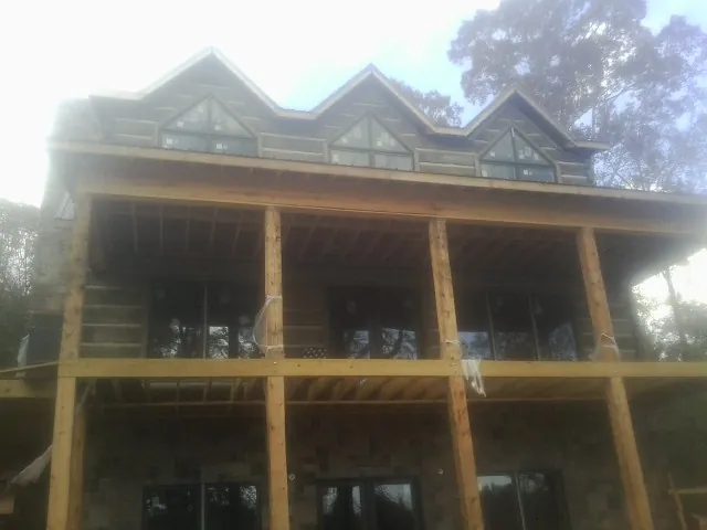 Dormers and porch framing on a large log home under construction — Roof Coating work by our crew in Sykesville