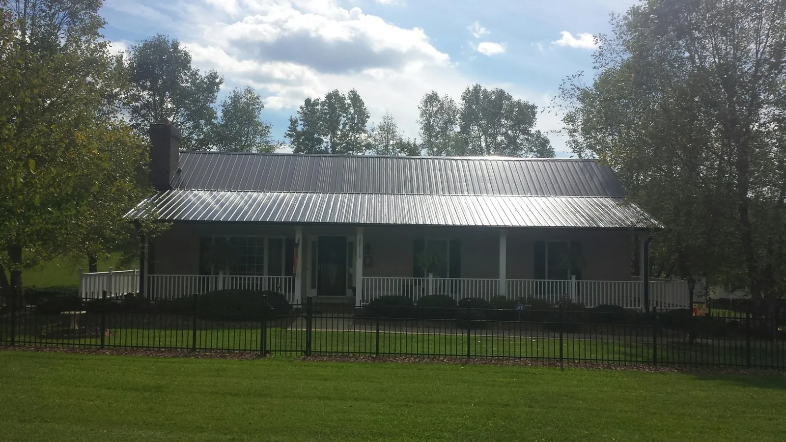 Gray metal roof on a brick ranch with a full width front porch — Gutter Guard Installation work by our crew in Sykesville