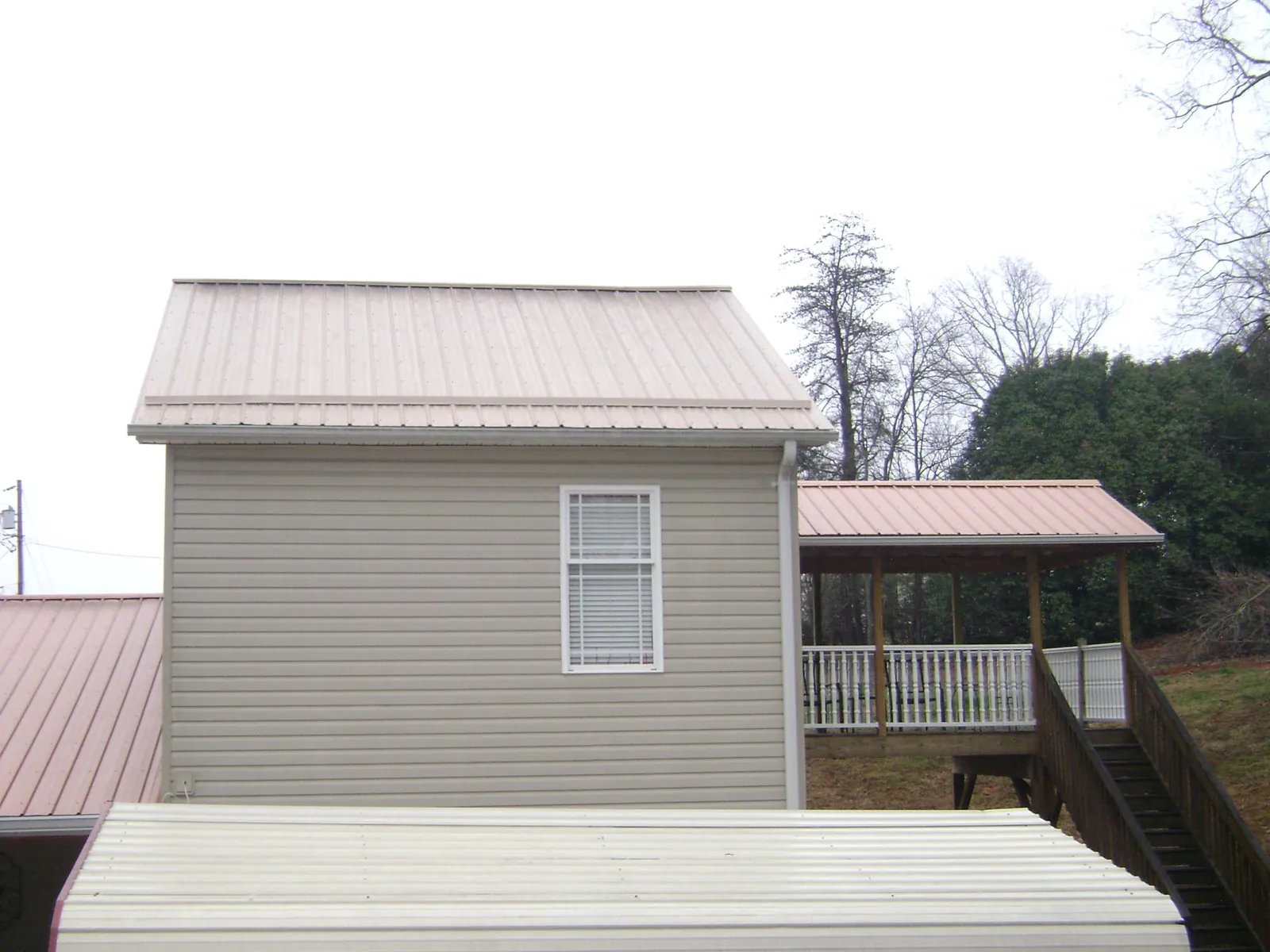Tan metal roofs on a two story addition and attached porch, from a Roof Replacement job in Sykesville