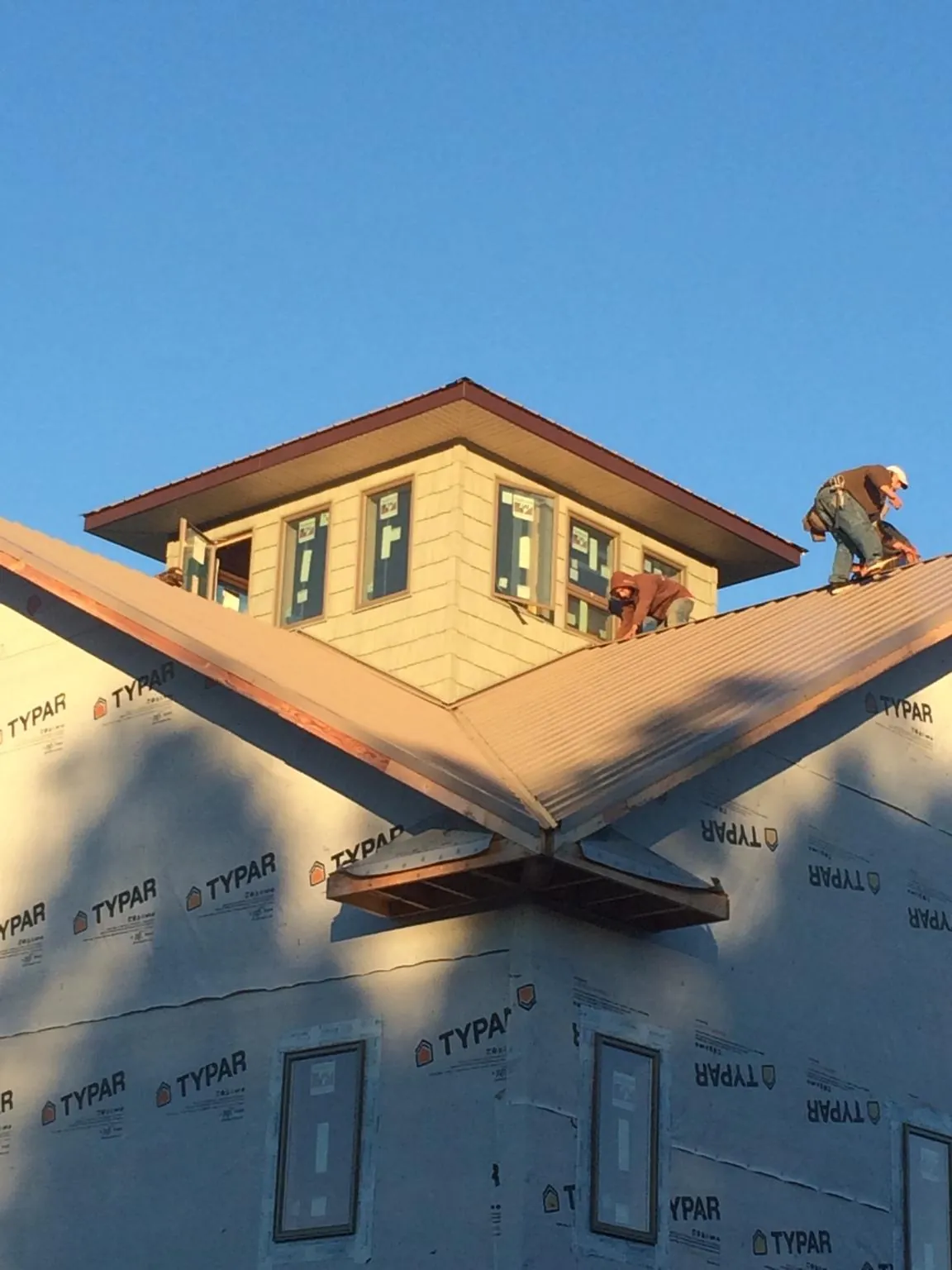 Roofers working around a rooftop cupola on a new metal roof at sunset — Roof Waterproofing in Sykesville by Roofing Brothers